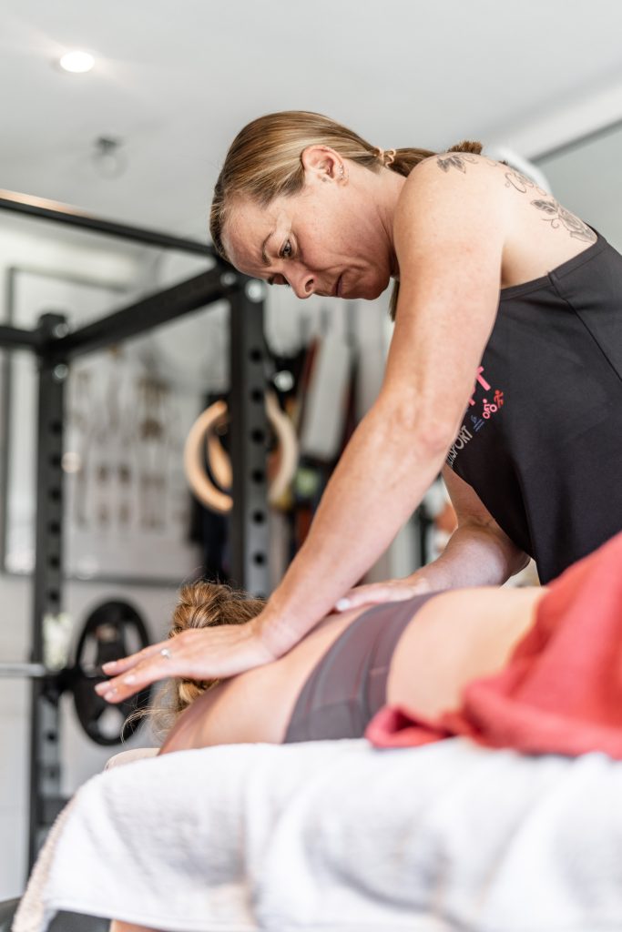 Dr Allie Park Crowne sports massaging the shoulders of a RedAlert PT client.